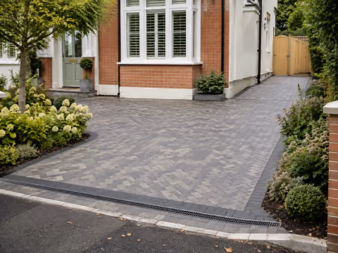 Grey herringbone block paved driveway with contrasting edge and drainage channel