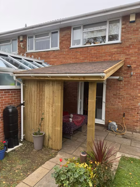 Solid-roof timber lean-to with cedar shingles and feather-edge screening outside a Chipping Sodbury back door