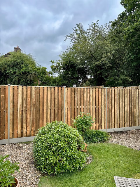 Completed hit-and-miss timber fencing with olive grey DuraPost supports in a planted garden