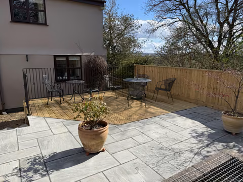New timber deck meeting a sandstone patio with feather-edge fencing around a Winterbourne garden